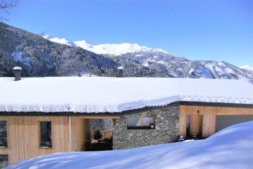 une maison recouverte de neige avec des montagnes en arrière-plan dans l'établissement Chalet le 1000 Thabor, à Valmeinier