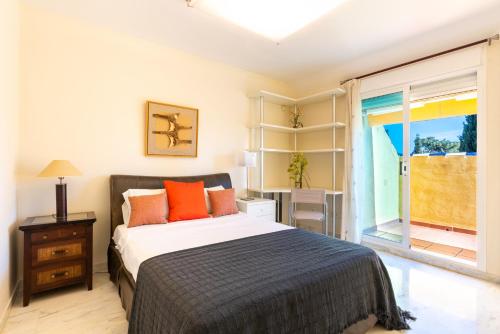 - une chambre avec un lit doté d'oreillers orange et une fenêtre dans l'établissement Bahia de Marbella - 3 bedroom beach apartment with sea view, à Marbella