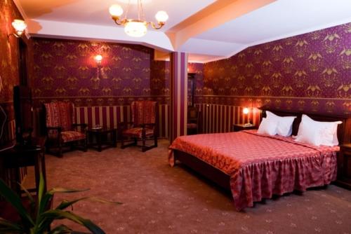 a bedroom with a bed and chairs in a room at Hotel Majestic in Iaşi