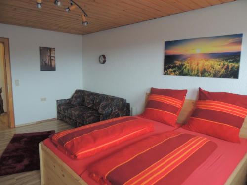 Dachsberg im SchwarzwaldにあるHaus Ingeborgのベッドルーム(赤いベッド1台、ソファ付)