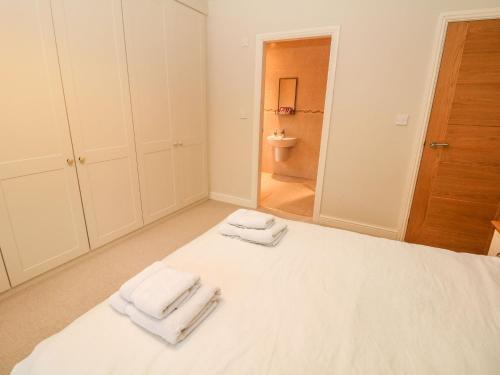 a bedroom with a white bed with towels on it at Glenhurst in Dronfield