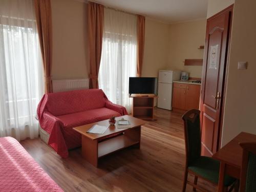 uma sala de estar com um sofá vermelho e uma mesa em Medgyaszay Panzió em Nagykanizsa