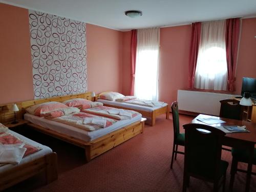 um quarto de hotel com duas camas e uma mesa e uma secretária em Medgyaszay Panzió em Nagykanizsa