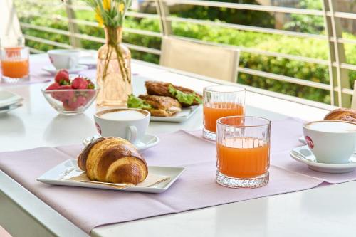 een tafel met een ontbijt van croissants en jus d'orange bij JUST SUITES in Cervia