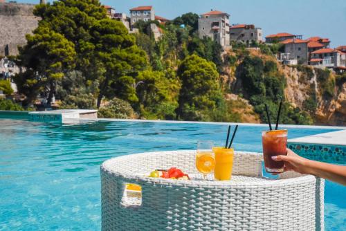una mesa con bebidas junto a la piscina en Hotel Maris, en Ulcinj