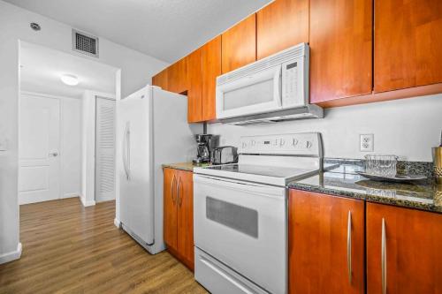 a kitchen with white appliances and wooden cabinets at Amazing cozy Condo in Brickell Miami in Miami