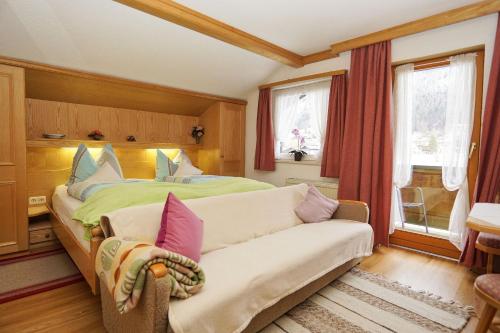 ein Schlafzimmer mit einem Bett, einem Sofa und einem Fenster in der Unterkunft Haus Regner in Reit im Winkl