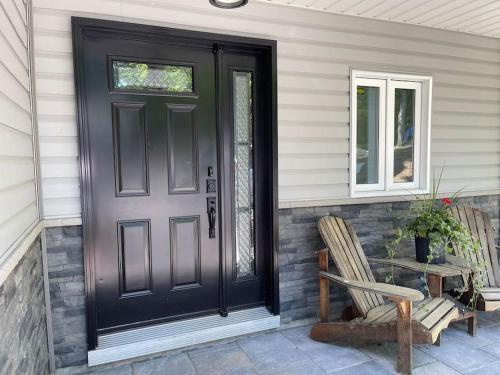 a black door on a house with a chair at SouthLake Cottage on The Lake. in Washago