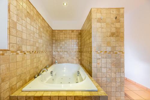 y baño con bañera y paredes de azulejos. en Villa Sa Tanca Den Lloses, en Can Furnet