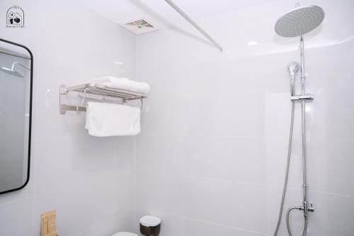 a white bathroom with a shower and a toilet at Chi's Homestay & Coffee in Hue