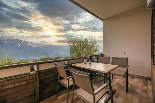 a table and chairs on a balcony with a view of mountains at Mösslacher's Ferienwohnungen in Hermagor