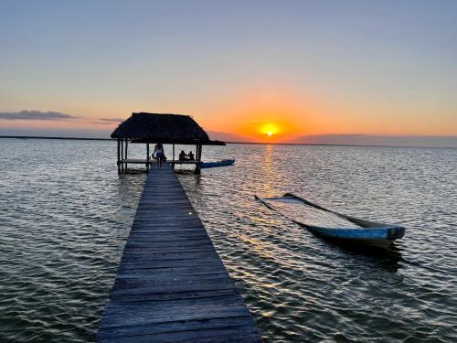 a dock with a hut and a boat on the water at Dos Mares Barefoot Luxury in El Cuyo