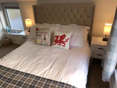 una camera da letto con un letto bianco con due cuscini sopra di Cardiff Coach House with Hot Tub & Log Fire a Cardiff