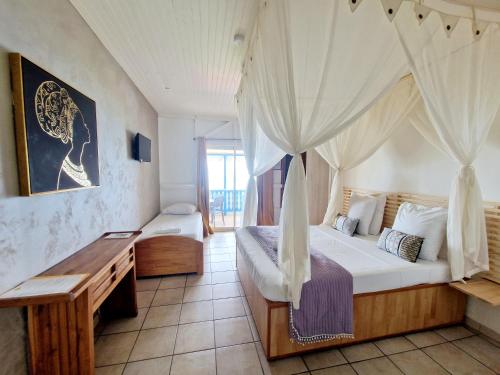 Schlafzimmer mit einem Bett mit Moskitonetz in der Unterkunft Hotel Le Manguier in Morne Pavillon