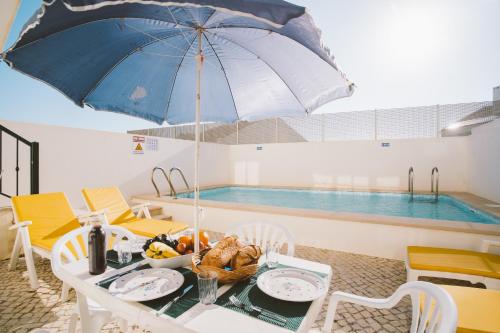 a table with an umbrella next to a swimming pool at Best Houses 31 - Seashell House in Baleal