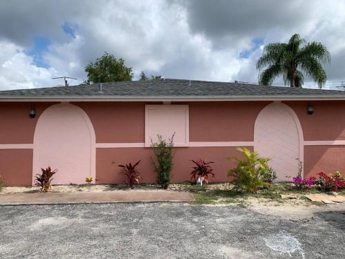 a pink house with palm trees in front of it at The Green Door Bungalow in Naples
