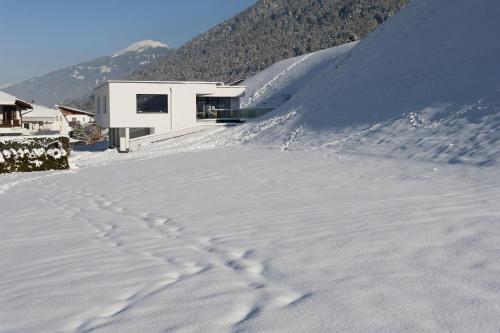 a house in the snow with footprints in the snow at Ferienwohnung Robi in Fulpmes