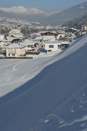 a snow covered hill with a town in the background at Ferienwohnung Robi in Fulpmes