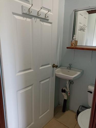 a bathroom with a white door and a sink at The Sweet Escape Cabinas in Sierpe
