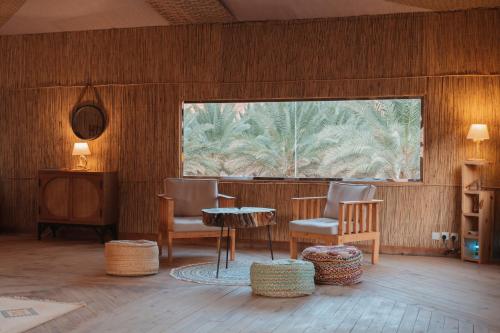 a room with chairs and a table and a window at 26North Glamping in Al Ula