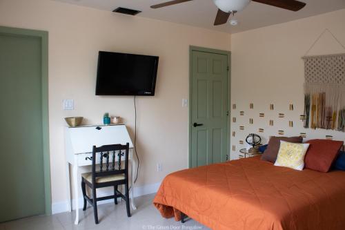 a bedroom with a bed and a television on the wall at The Green Door Bungalow in Naples