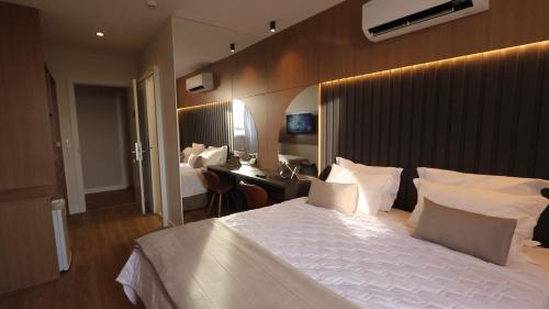 um quarto com uma grande cama branca e uma secretária em Açu Hotel em São João da Barra
