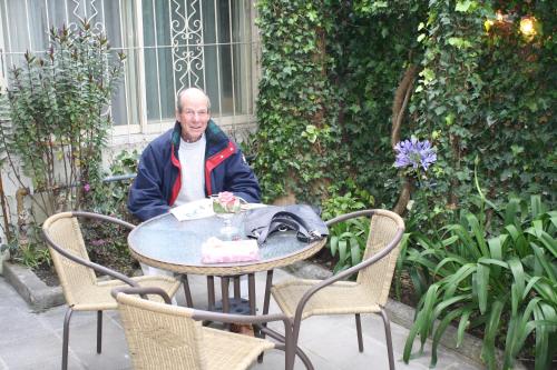 a man sitting at a table in a garden at City Art Hotel Silberstein in Quito