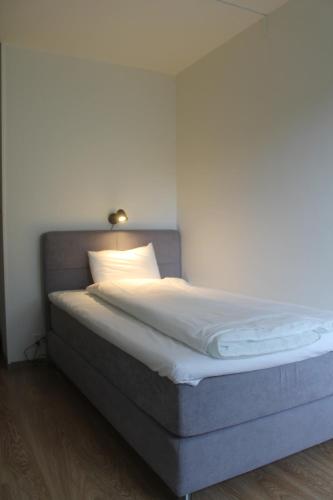 a bed with white sheets and a light on top at Millners Plaza in Tibro