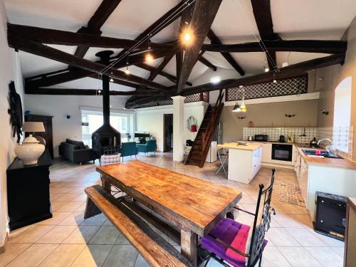 uma grande cozinha e sala de estar com uma mesa de madeira em Batîsse le Moulinage du Luol avec parc arboré em Saint-Privat