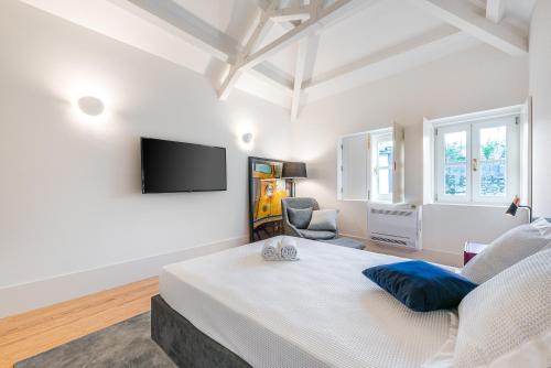 a white bedroom with a large bed and a flat screen tv at Door 65 - Historical Center Apartments in Porto