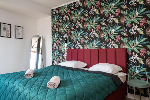 a bedroom with a green bed with a tropical wallpaper at LeoApart in Wrocław