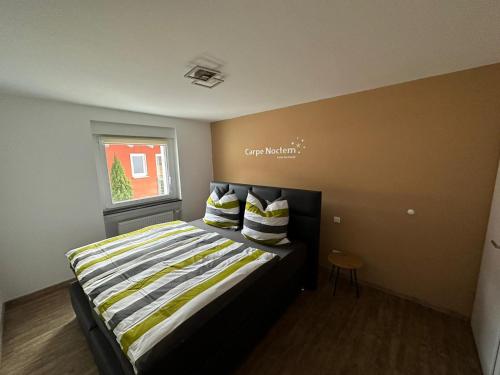 Un dormitorio con una cama con almohadas a rayas y una ventana en Casa Ideal, en Bruchsal