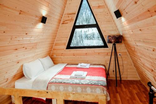 łóżko w drewnianym domku z oknem w obiekcie Cozy chalet in Mestia w mieście Mestia