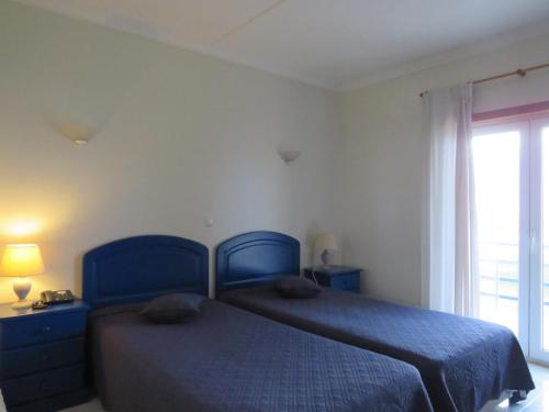 a bedroom with a blue bed and a window at Hotel Apartamento Praia Azul in Santa Cruz