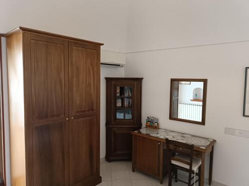 Habitación con armario de madera, mesa y espejo. en NINO'S IN NOCELLE en Positano