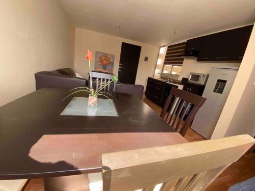 a dining room table with a vase with a flower on it at Hermoso departamento en Cuautlancingo in Santa María Coronanco