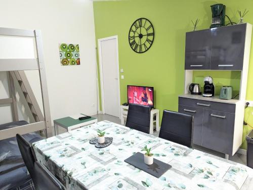 a dining room with a table and a clock on the wall at Appartement entier meublé à Beaumont proche Futuroscope et Poitiers Technopole in Beaumont