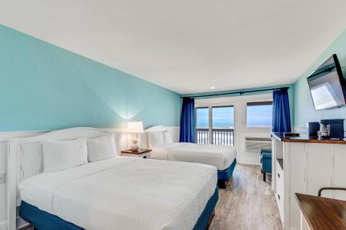 Una habitación de hotel con dos camas y balcón. en John Yancey Oceanfront Inn, en Kill Devil Hills