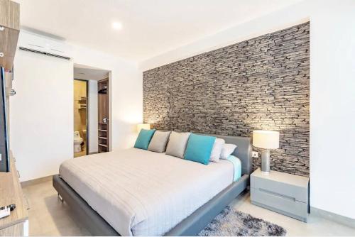 a bedroom with a bed and a brick wall at Tolok condo at Icono Playa in Playa del Carmen