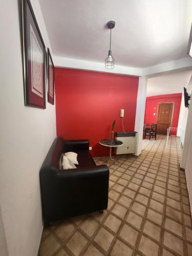 sala de estar con sofá negro y pared roja en DPTO BALCARCE en Salta