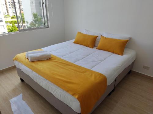 1 cama grande con almohadas amarillas en una habitación en Apartamento en Hacienda Peñalisa Ceiba, Sol, Piscina y descanso, en Girardot