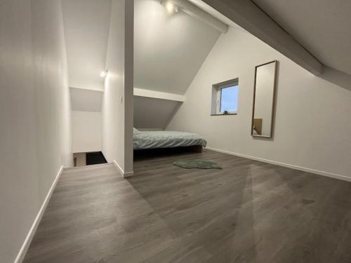 Cette chambre blanche comprend un lit et un miroir. dans l'établissement le Grand Vivier- 68 M2, à Héron