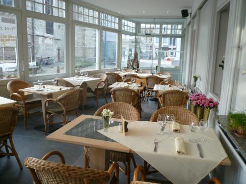 a restaurant with tables and chairs and windows at Hotel La Barakka in Lokeren