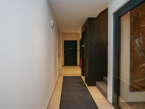 a hallway with white walls and a black carpet at Alte Bildhauerei in Aurach bei Kitzbuhel