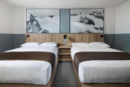 two beds in a room with snow covered mountains at The Approach Hotel in Panorama