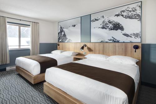 two beds in a hotel room with mountains on the wall at The Approach Hotel in Panorama