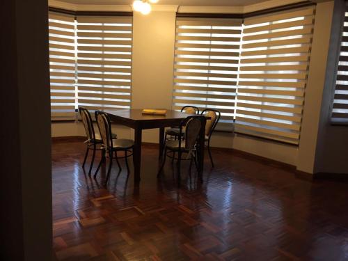 a dining room with a table and chairs and windows at Tu experiencia comienza aquí Departamento 3D 3C Achumani a pasos de la calle 29 in La Paz