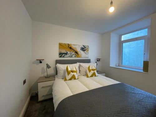 a bedroom with a large bed and a window at Newly rennovated 1-bedroom serviced apartment, walking distance to Hospital or Train Station in Newport