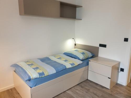 ein kleines Schlafzimmer mit einem Bett und einem Nachttisch in der Unterkunft Apartma Vič Ljubljana in Ljubljana