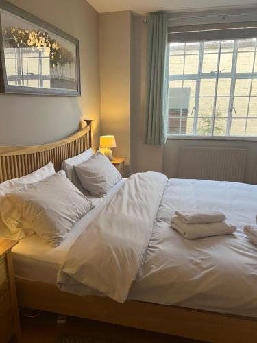 a bedroom with a bed with white sheets and a window at 2 Bedroom Apartment just off Kings Road in London